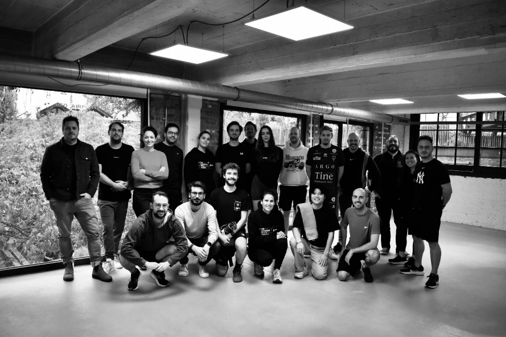 Black and white group photo of the 9ID team in a modern office.